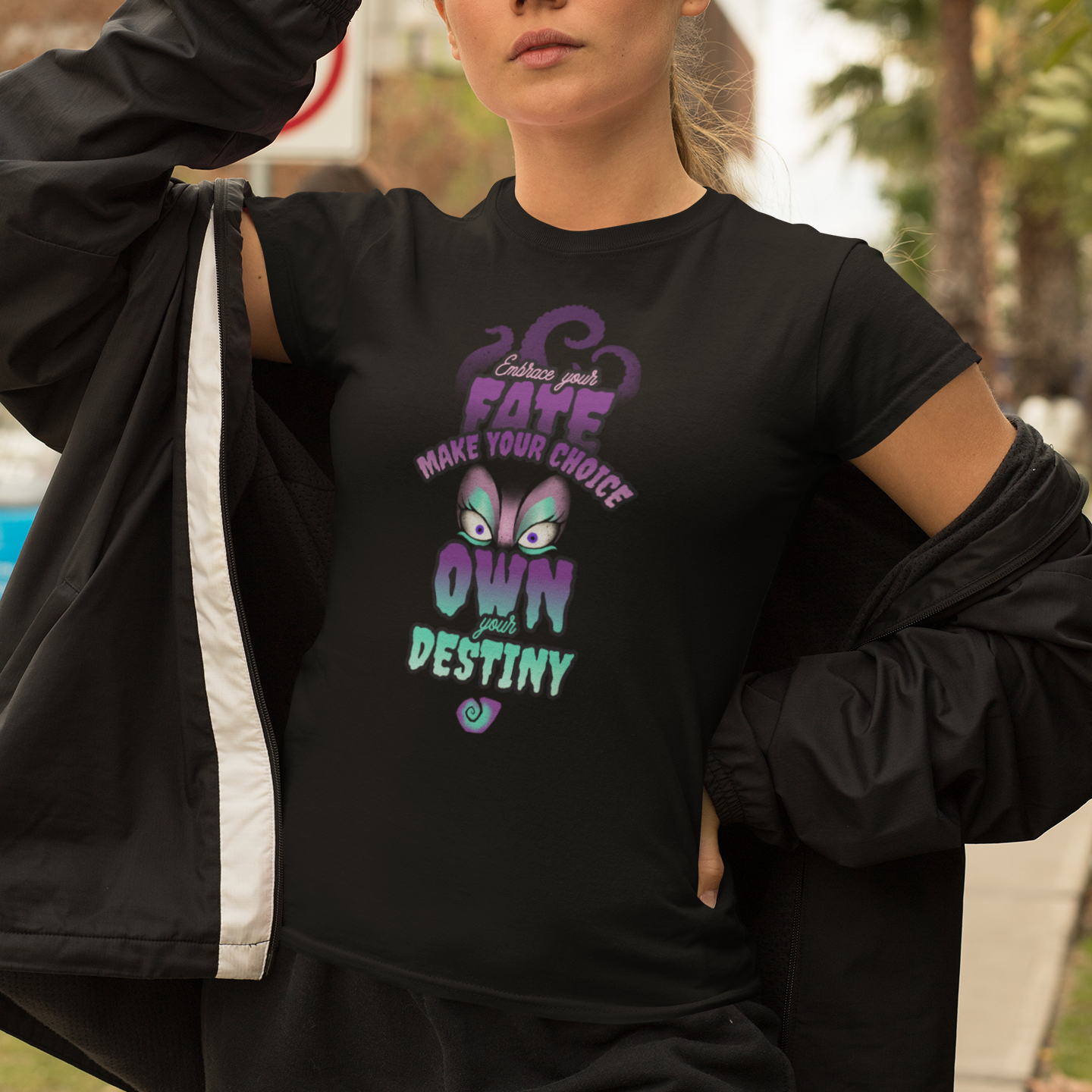 Person wearing a black t-shirt with colorful text and graphics, standing outdoors.